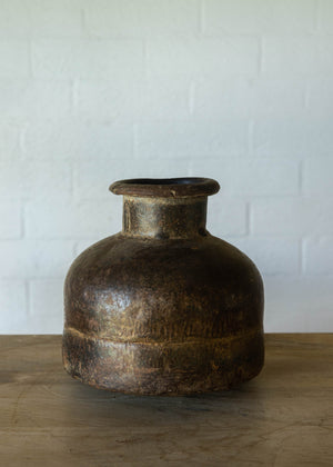 Rustic iron pot from India with a large base, a narrow neck and  a turned lip at the opening. Width and height equal at approx 30cm. 