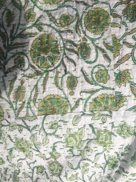 A close up image of 100% cotton Kantha quilt with flower pattern in green on a white background.  The kantha quilt is a hand made textile from India, traditionally created as a wedding quilt and is hand stitched throughout.  