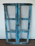 Solid teak gates from India. Rustic blue  paint finish and vertical iron bars in 3 timber framed sections. Solid iron hinges on the sides of the door at the top and bottom. Iron latch, brass handles  and iron details . Perfect for securing pets, homes and children. Good outside as garden gates.