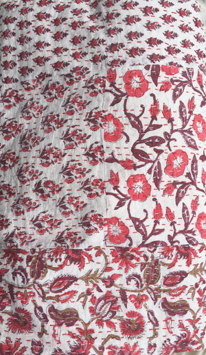 A close up image of 100% cotton Kantha quilt with flower pattern in burgundy and reds on a white background.  The kantha quilt is a hand made textile from India, traditionally created as a wedding quilt and is hand stitched throughout.  
